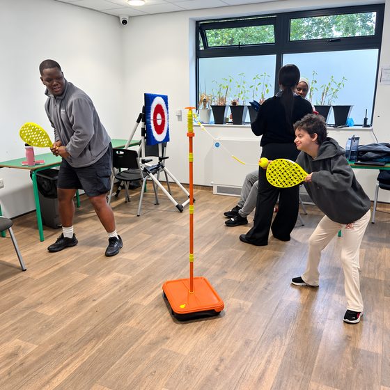 Two members playing a target bat-and-ball game together in the activities room.