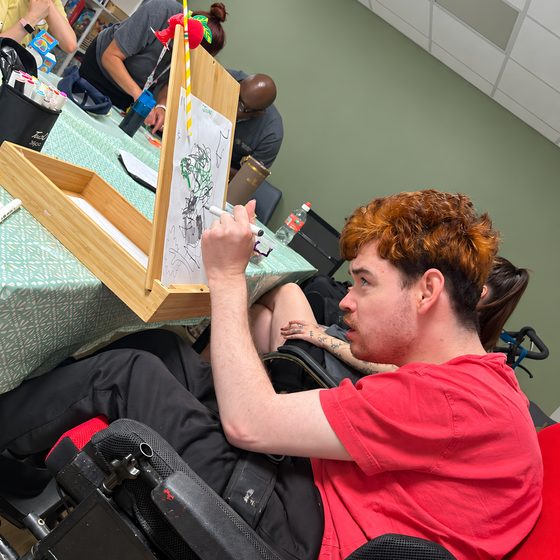 A member using an easel to draw during an arts and crafts session.