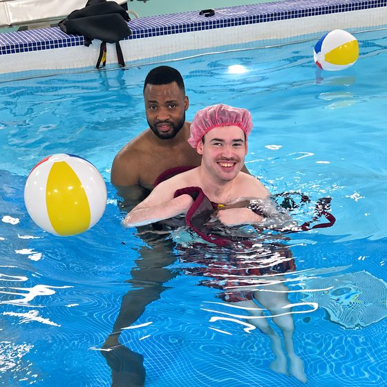 Two members playing with a beach ball together in the warm hydrotherapy pool.