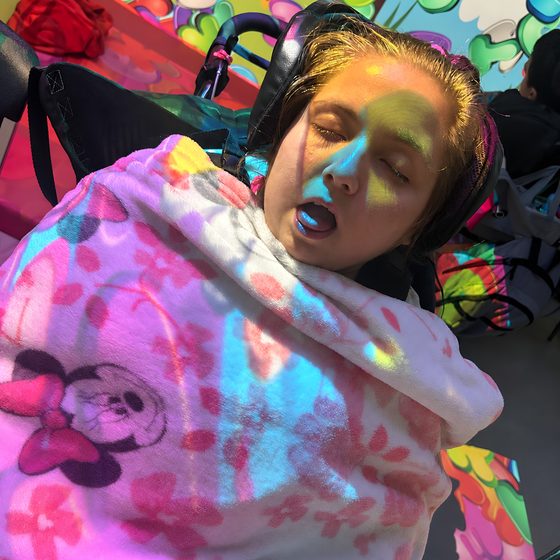 Coloured light patterns projected over a member wrapped in a soft blanket in the immersive room.
